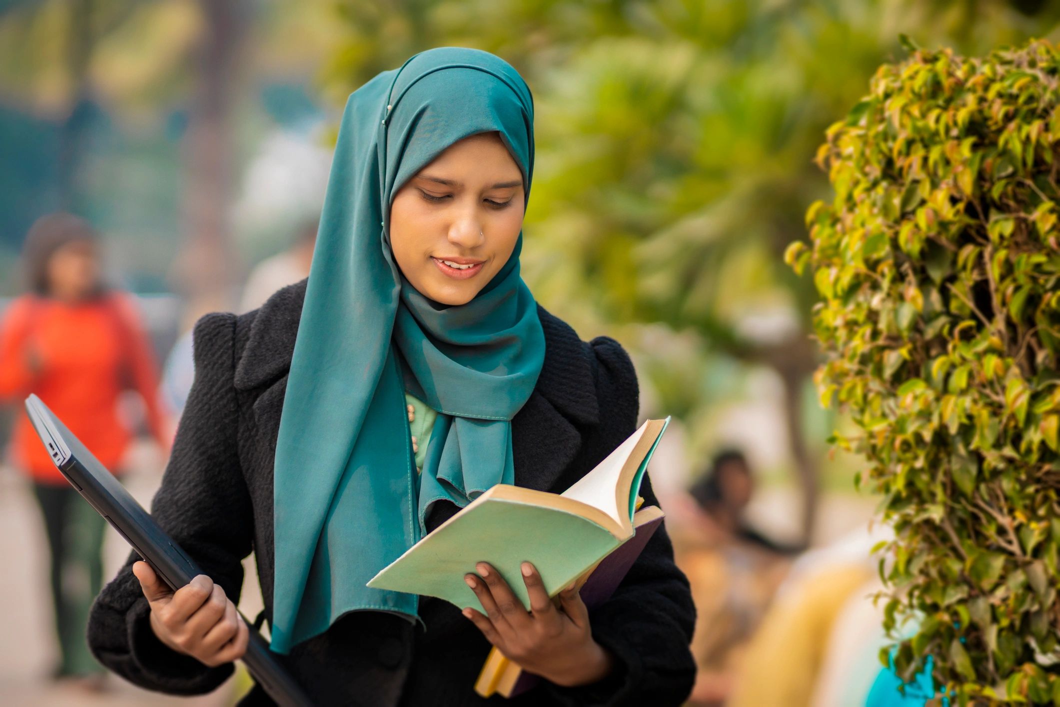 College student with laptop and book on campus